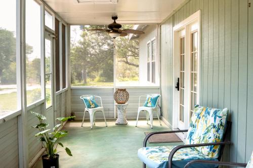 a screened porch with two chairs and two windows at Hadley's House - A Country 3 Bdrm with Screened-In Porch in New Braunfels