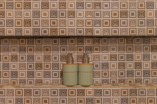 two candles sitting on a shelf with a tiled wall at Lavender - Taman Tanda in Bedugul
