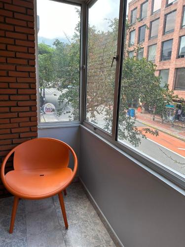 a orange chair sitting in front of a window at Center City Flats - Apartments in El Poblado near Park Lleras, Medellin! in Medellín