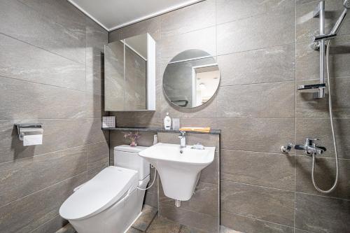 a bathroom with a toilet and a sink and a mirror at Haedam House in Jeju