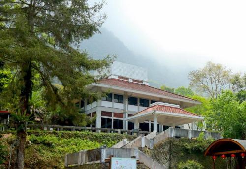a large white house on a hill with trees at Howard Resort Xitou in Lugu