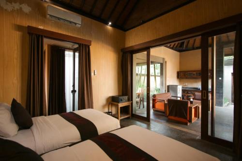 a hotel room with two beds and a living room at Gino Feruci Villa Ubud by KAGUM Hotels in Ubud