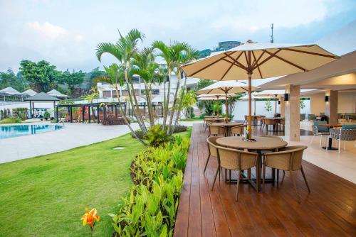 um pátio com mesas e guarda-sóis e um parque infantil em Surya Hotel & Cottages Prigen em Tretes