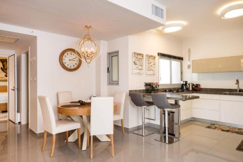 a kitchen with a table and a clock on the wall at Beautiful Apts w/ Large Balcony & Parking by Sea N' Rent in Tel Aviv