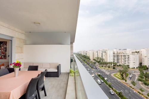 a balcony with a table and chairs and a highway at Beautiful Apts w/ Large Balcony & Parking by Sea N' Rent in Tel Aviv