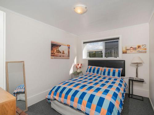 1 dormitorio con cama y espejo en Beside the sea, park up and relax - Just 20 steps to the beach - Wi-Fi & Linen, en Whitianga