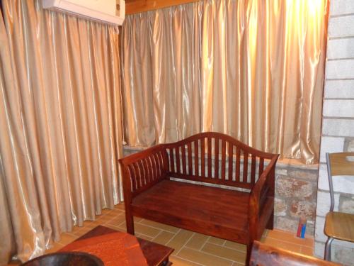 a wooden bench sitting in front of a window with curtains at Menina Farm Kalamata Countryside in Perivolákia