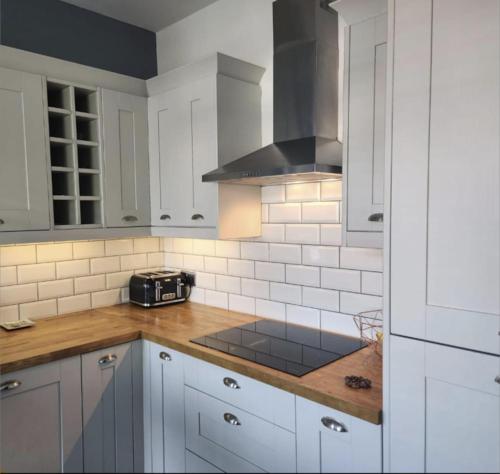 a kitchen with white cabinets and a counter top at Cosy Worsley Home with a Garden Bar! in Manchester