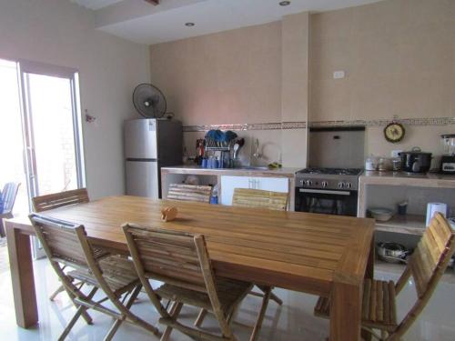 uma cozinha com uma grande mesa de madeira e cadeiras em Casa de Playa en Colan Casa Merino. em Paita