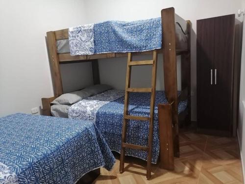 a bunk bed with a ladder next to a bed at Casa de Playa en Colan Casa Merino. in Paita