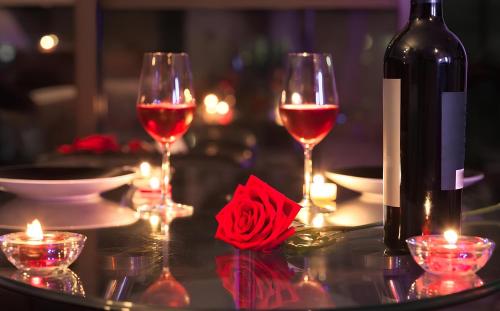 a table with two glasses of red wine and candles at La Charm Hoi An Hotel & Spa in Hoi An