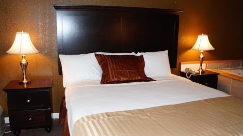 a bed in a hotel room with two lamps at Americas Best Value Inn & Suites Kansas City in Grandview