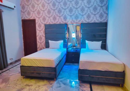 two beds in a room with blue lights on them at Red Fort Hotel Gulberg in Lahore