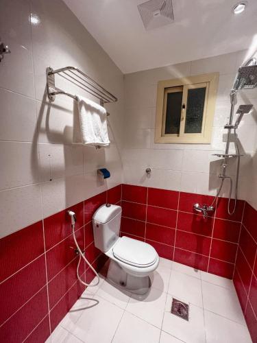 a bathroom with a white toilet and red tiles at رواح للشقق المخدومة السداد in Taif