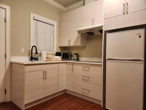 eine Küche mit weißen Schränken und einem weißen Kühlschrank in der Unterkunft Richmond BC Canada 1-Bedroom Suite in Richmond