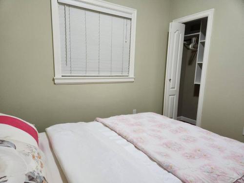 ein Schlafzimmer mit einem Bett und ein Fenster mit einer Decke in der Unterkunft Richmond BC Canada 1-Bedroom Suite in Richmond
