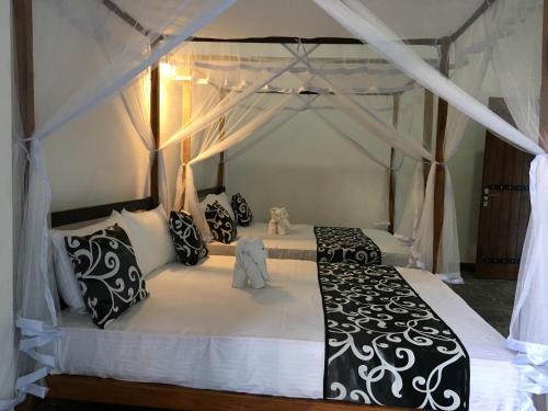 a bedroom with a black and white canopy bed at Peacock Riverside Eco Lodge in Udawalawe