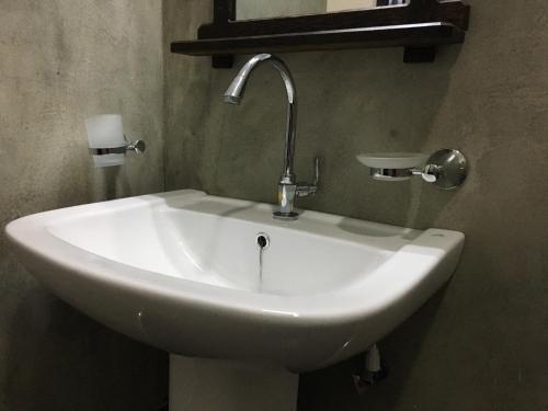 lavabo blanco con grifo en el baño en Peacock Riverside Eco Lodge en Udawalawe