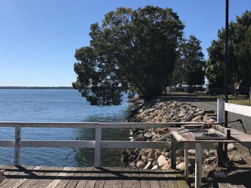 a picnic table next to a fence next to the water at Fishing Haven Holiday Park in Palmers Island