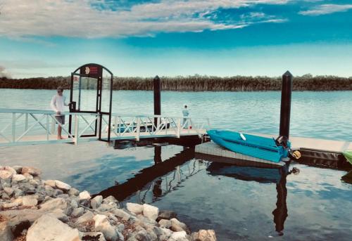a man standing on a dock with a boat on the water at Fishing Haven Holiday Park in Palmers Island