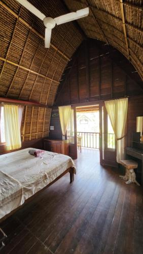 a large bedroom with a bed in a straw hut at Suka Beach Bungalow in Nusa Lembongan