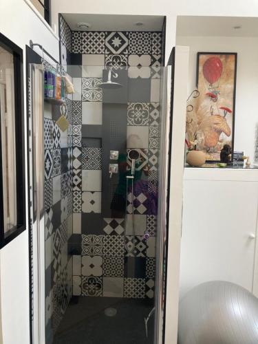 a bathroom with a shower with black and white tiles at Maison Charme in Ernée