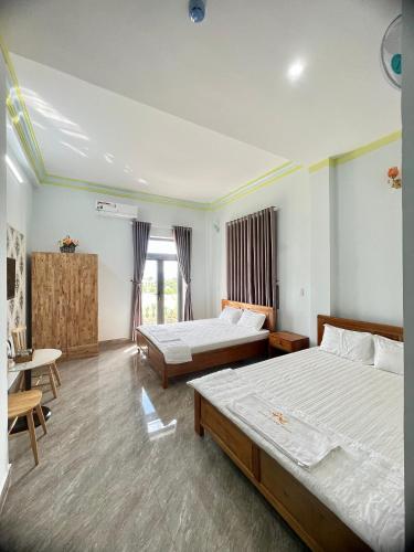 1 dormitorio con 2 camas, escritorio y ventana en KHÁCH SẠN HOÀNG QUANG, en Biđong