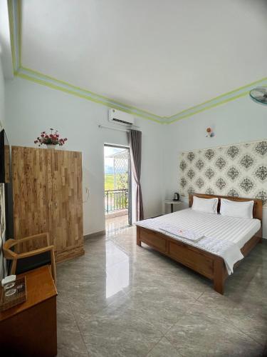 1 dormitorio con 1 cama grande y balcón en KHÁCH SẠN HOÀNG QUANG, en Biđong