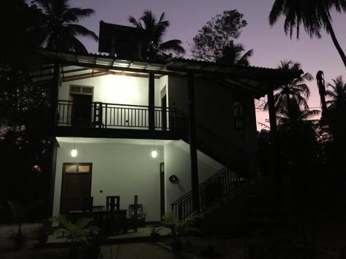 a house with a balcony at night at Peacock Riverside Eco Lodge in Udawalawe