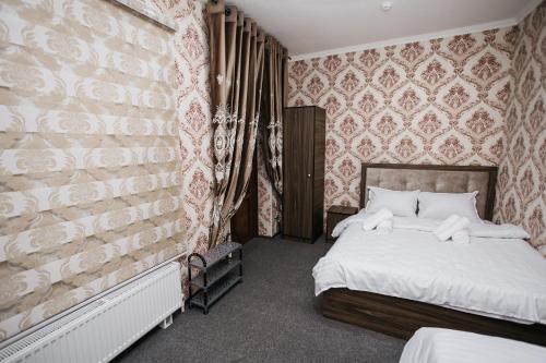 ein Schlafzimmer mit einem Bett und einer Wand in der Unterkunft Nazarxan Hotel in Samarkand