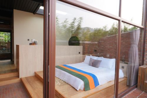 a bedroom with a bed and a large window at Brickyard Retreat at Mutianyu Great Wall Adjoin to Mutianyu Great Wall - Room with the View of Great Wall - Chinese massage experience - Vehicle Shuttle Service - International Catering - SPA& Nail Beauty Facilities in Huairou