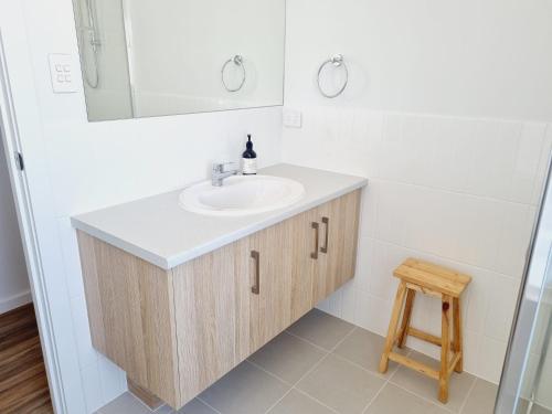 a bathroom with a sink and a mirror and a stool at Surfmist House in Robe