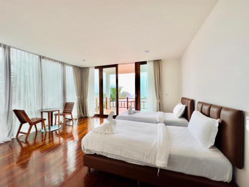 a bedroom with two beds and a table and chairs at PP Mountain Beach Resort in Phi Phi Islands