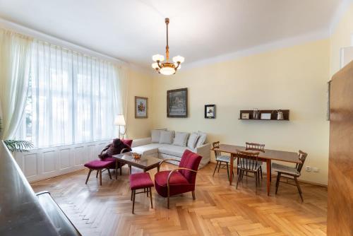uma sala de estar com um sofá, uma mesa e cadeiras em Historic Apartment em Praga