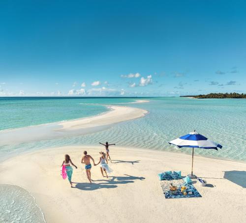 a group of people on a beach with an umbrella at Kandima Maldives in Kudahuvadhoo