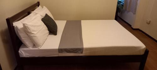 a small bed with white sheets and pillows on it at Balay 8 Suites in Silay