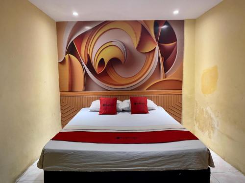 um quarto com uma cama com um quadro na parede em RedDoorz near Gedung Kesenian Palopo em Palopo