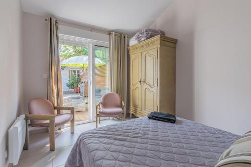 Un dormitorio con una cama y dos sillas y una ventana. en Maison Le Moulleau, en Arcachon