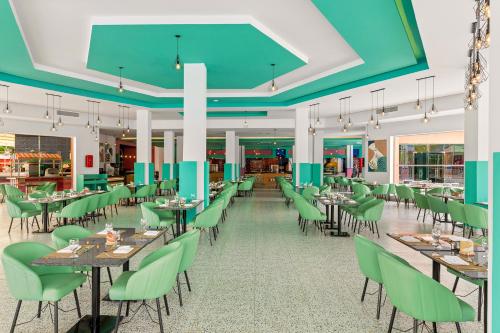 a dining room with tables and green chairs at Pickalbatros Jungle Aqua Park - Neverland Hurghada in Hurghada