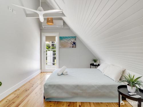 ein weißes Schlafzimmer mit einem Bett und einem Deckenventilator in der Unterkunft A- FRAME ON FERGUSON! in Emu Park