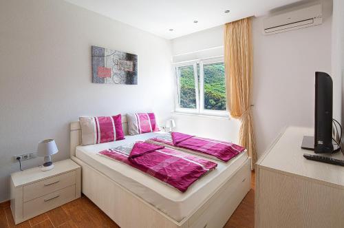 a bedroom with a bed with pink sheets and a window at Montelux Apartments in Budva