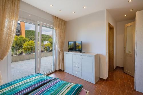 a bedroom with a bed and a television and a balcony at Montelux Apartments in Budva