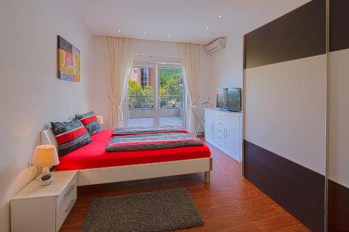 a bedroom with a red bed and a window at Montelux Apartments in Budva