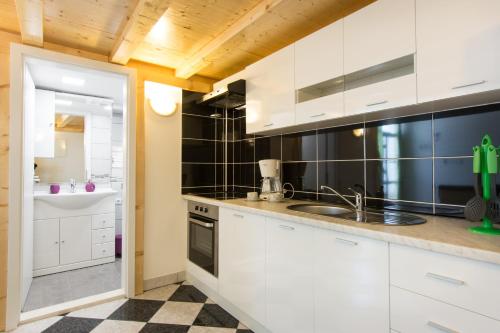 a kitchen with white cabinets and a sink at Apartments Storia in Trogir