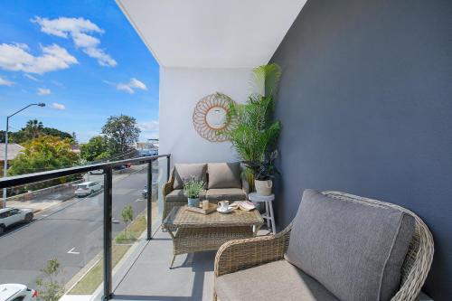a balcony with two chairs and a table and a street at HOT Stylish Costal 3 ensuite apartment on Redcliffe, Brisbane in Redcliffe