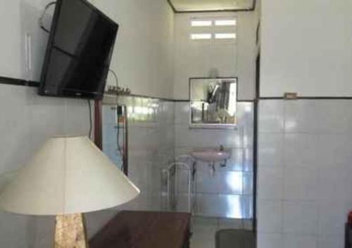 baño con TV en la pared y lámpara en Hotel Agung Putra, en Banyumas