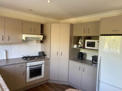 a kitchen with white cabinets and a white refrigerator at The Sun Trap in Mangawhai Heads in Mangawhai