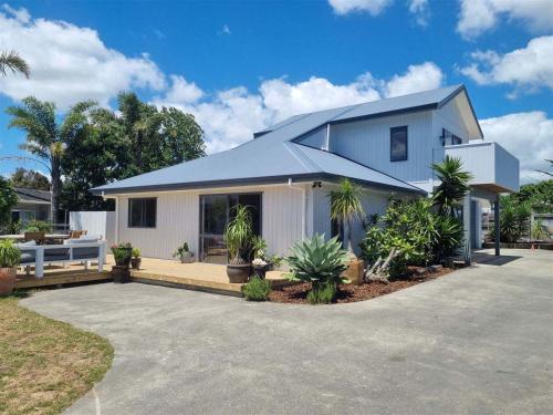 a white house with a blue roof at The Sun Trap in Mangawhai Heads in Mangawhai