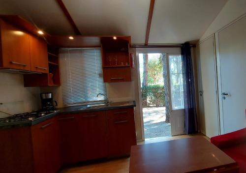 a kitchen with wooden cabinets and a door to a yard at Camping Bella Vista in Ceriale