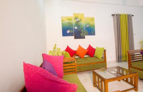 a living room with a couch with colorful pillows at Artic Holiday Homes-Apartments in Weliweriya